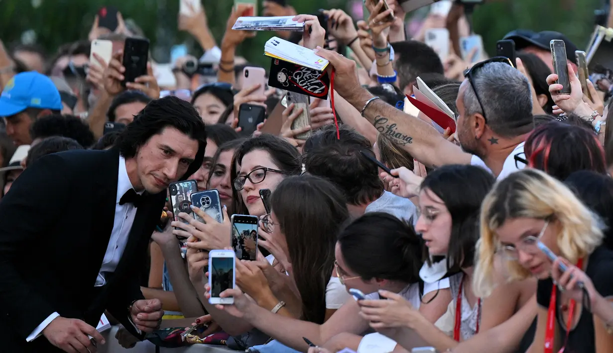 Adam Driver berpose untuk foto selfie saat ia tiba untuk Upacara Pembukaan dan pemutaran film "White Noise" (31/8/2022) selama Festival Film Internasional Venesia ke-79 di Lido di Venezia di Venesia, Italia. Adam melayani ajakan foto selfie penggemar sebanyak mungkin. (Tiziana FABI/AFP)