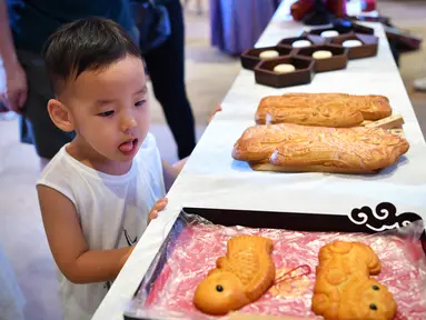 Seorang anak melihat pameran kue bulan dalam perayaan Festival Pertengahan Musim Gugur di Museum Hainan di Haikou, ibu kota Provinsi Hainan, 1 Oktober 2020. Masyarakat di seluruh China menikmati beragam makanan lezat selama libur Hari Nasional dan Festival Pertengahan Musim Gugur. (Xinhua/Guo Cheng)