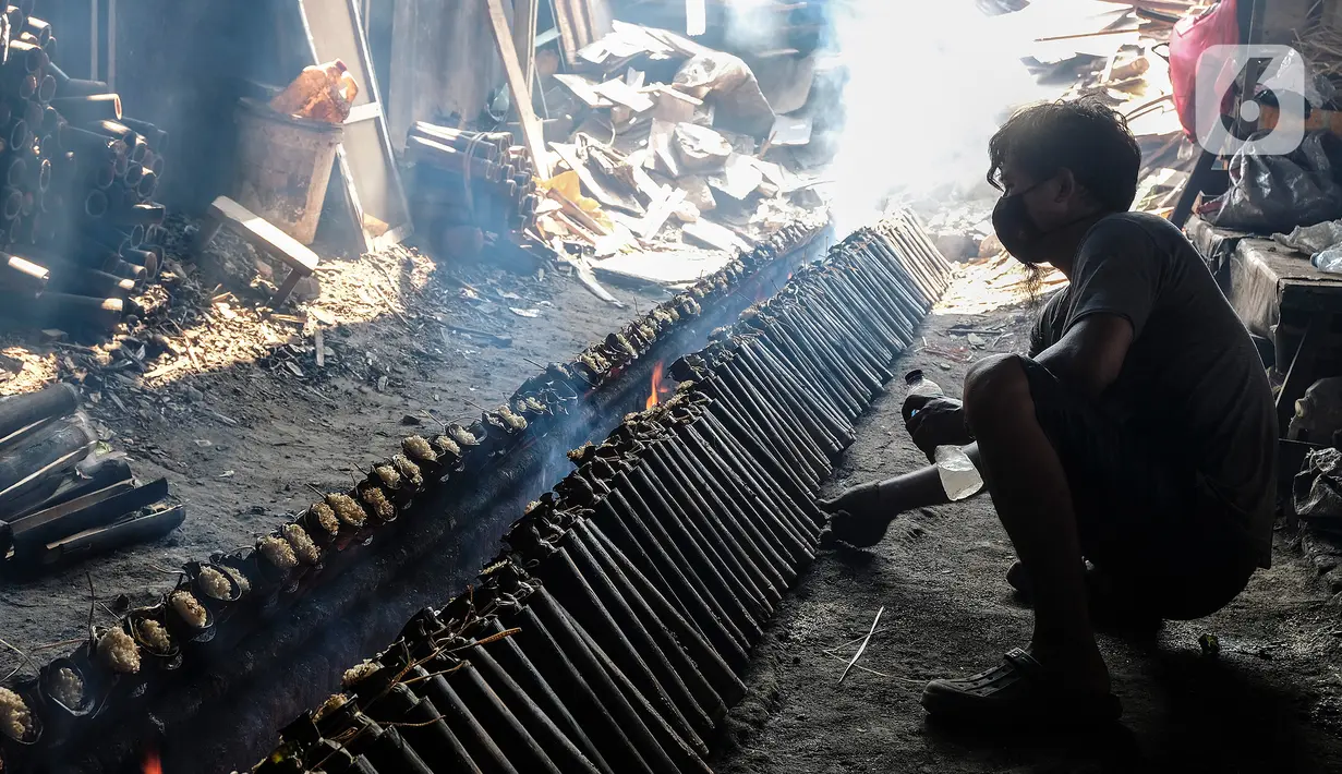 Pekerja membakar lemang yang sudah dibungkus daun pisang dan dimasukkan ke dalam bambu di industri pembuatan lemang kawasan Senen, Jakarta, Selasa (27/4/2021). (Liputan6.com/Johan Tallo)