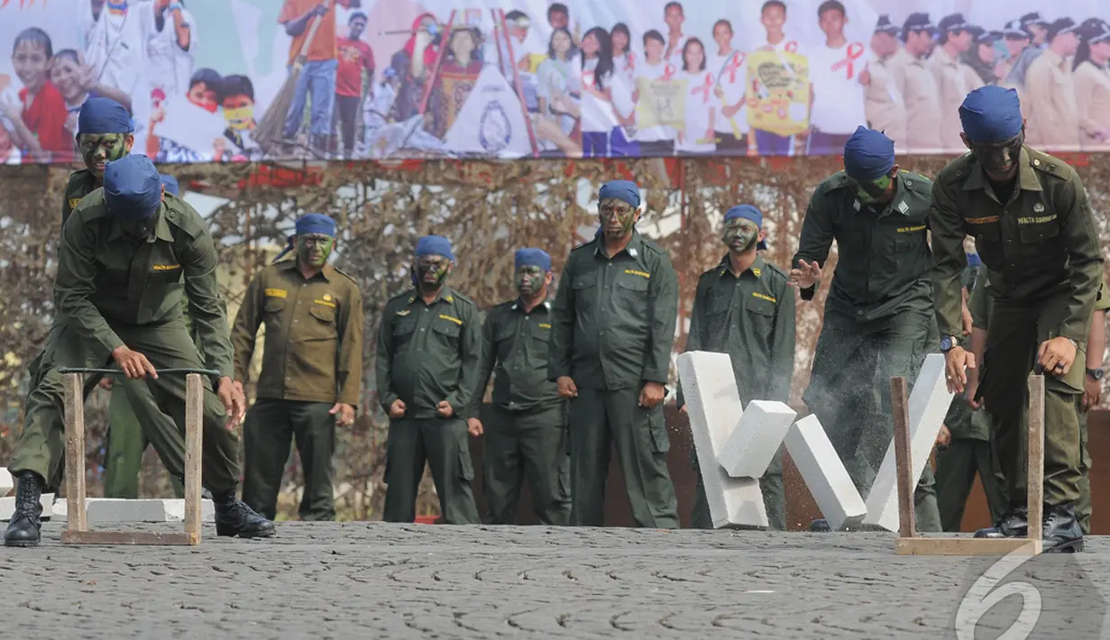 Anggota Kantor Kesehatan Pelabuhan (KKP) melakukan atraksi mematahkan besi dragon dan sebuah batu bata saat Upacara Peringatan Hari Kesehatan Nasional ke-50, Jakarta, Rabu (12/11/14) (Liputan6.com/Herman Zakharia)