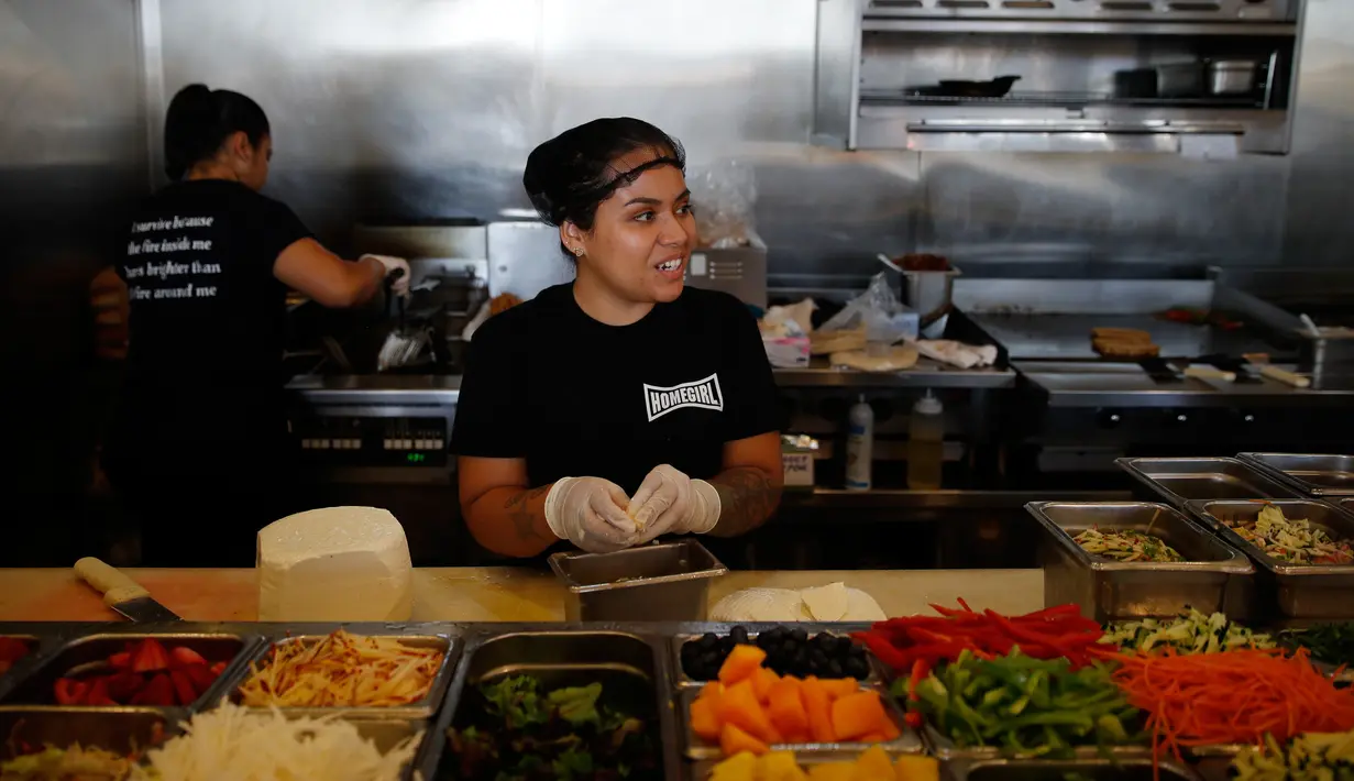 Maria Hidalgo (26) menyiapkan menu makanan di dapur Homegirl Cafe, Los Angeles, Senin (16/7). Kafe yang menyediakan sarapan dan makan siang khas Latin ini menawarkan pengalaman bersantap unik dengan mempekerjakan para mantan anggota geng. (AP/Jae C. Hong)