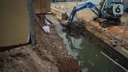 Alat berat mengeruk beton turap saluran air yang longsor di kawasan Jagakarsa, Jakarta, Kamis (17/9/2020). Selain karena hujan lebat, longsor diduga karena erosi tanah akibat pembuangan saluran air pencuci piring dan toilet dari warung makan di sekitar bantaran. (Liputan6.com/Immanuel Antonius)