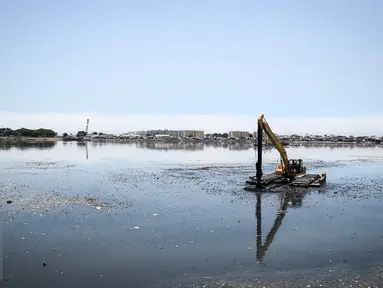 Sebuah alat berat mengeruk endapan lumpur di Waduk Pluit, Jakarta, Kamis (24/3/2016). Pengerukan itu bertujuan untuk mengangkat endapan lumpur dan sampah yang mengakibatkan pendangkalan waduk. (Liputan6.com/Faizal Fanani)