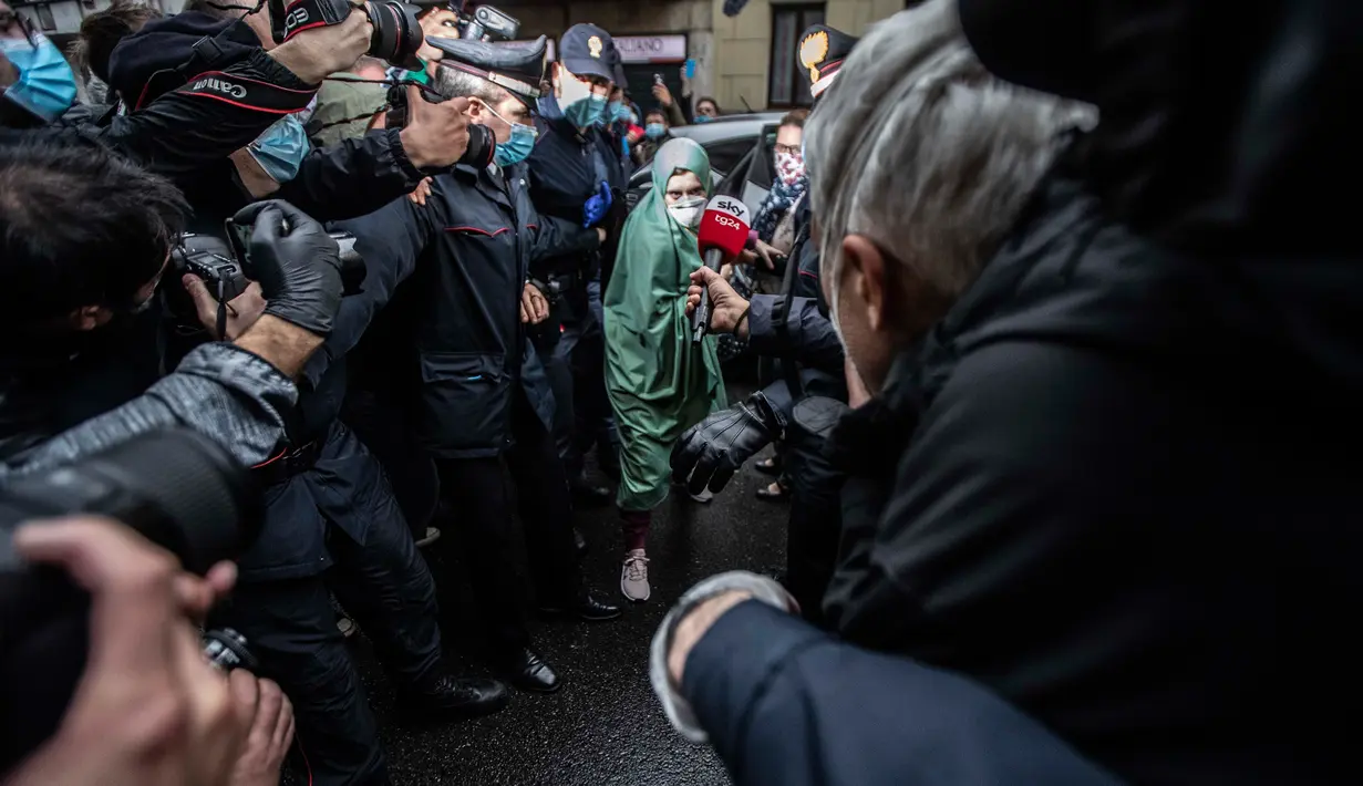 Petugas bantuan Italia bernama Silvia Romano yang dibebaskan oleh militan Somalia, dikawal polisi Italia (Carabinieri), tiba di rumahnya di Milan, 11 Mei 2020. Silvia, 25 tahun, memutuskan masuk Islam setelah dirinya diculik dari kota pesisir tenggara Kenya pada November 2018. (AP/Luca Bruno)