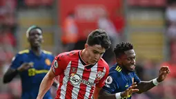 Pemain Southampton Tino Livramento (tengah) berebut bola dengan pemain Manchester United Fred (kanan) pada pertandingan Liga Inggris di Stadion St Mary, Southampton, Inggris, 22 Agustus 2021. Pertandingan berakhir imbang 1-1. (Glyn KIRK/AFP)