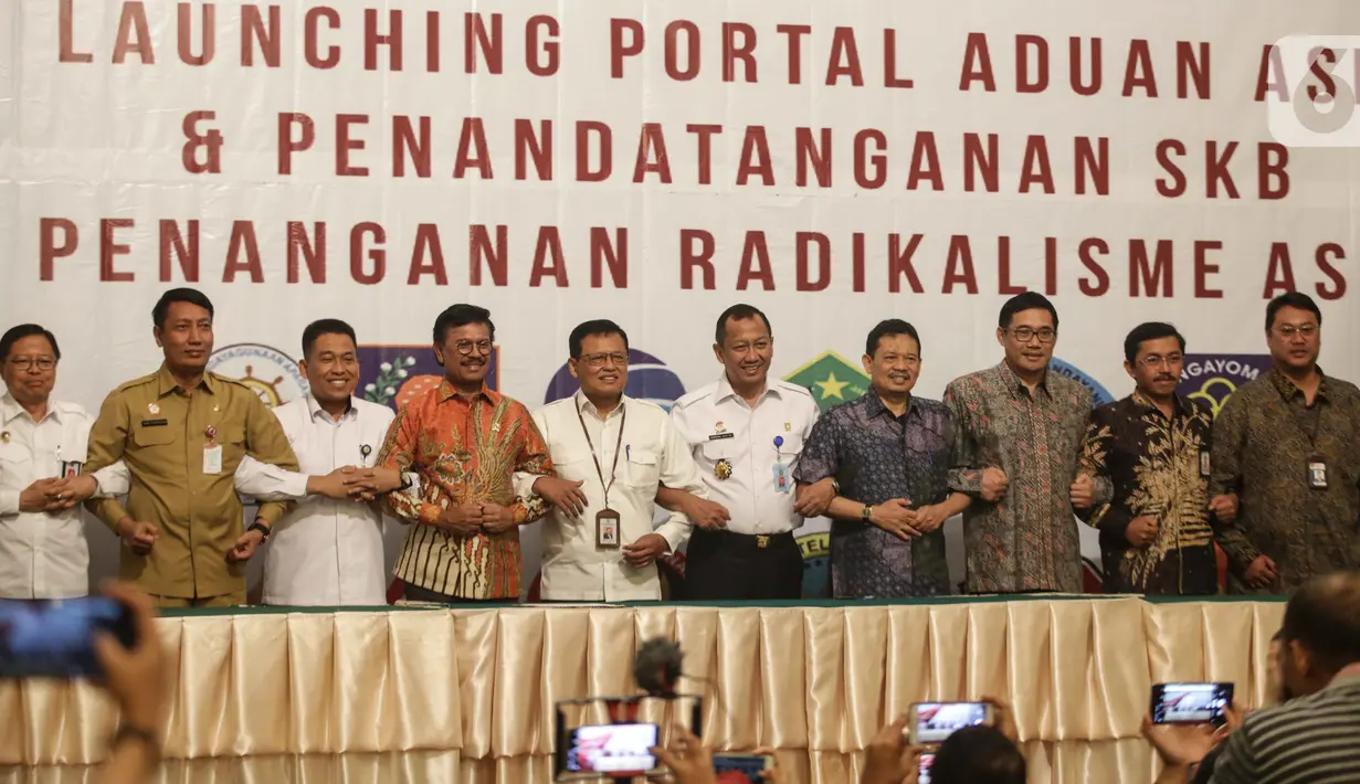Menkominfo Johnny G. Plate (keempat kiri) bersama sebelas Kementerian dan lembaga negara  usai penandatangan kerja sama pembuatan portal aduan untuk aparatur sipil negara (ASN), Jakarta, Selasa (12/11/2019). Portal ini bisa melaporkan ASN yang diduga terpapar radikalisme (Liputan6.com/Faizal Fanani)