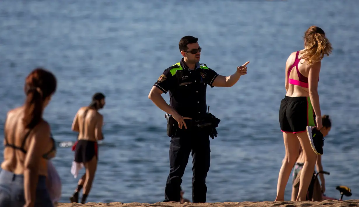 Petugas polisi meminta orang-orang untuk tidak duduk sambil berpatroli di pantai di Barcelona, Spanyol, Rabu, (20/5/2020). Barcelona mengizinkan orang untuk berjalan di pantai untuk pertama kalinya sejak dimulainya penguncian virus coronavirus lebih dari dua bulan lalu. (AP Photo/Emilio Morenatti)