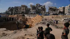 Warga Palestina menyaksikan aktivitas pekerja Mesir yang menggunakan alat berat untuk mencari jenazah para sandera di Kota Hamad, Khan Younis, di Jalur Gaza selatan, Selasa 28 Oktober 2025. (AP Photo/Abdel Kareem Hana)