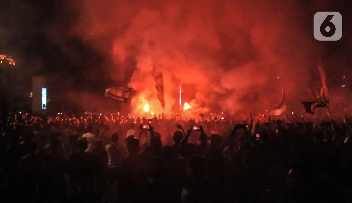 Massa yang tergabung dalam Ultras Garuda Jakarta mengikuti aksi menyalakan lilin dan tabur bunga untuk korban kerusuhan Stadion Kanjuruhan Malang di depan Stadion Gelora Bung Karno (GBK), Jakarta, Minggu (2/10/2022). Aksi tersebut sebagai aksi solidaritas antar suporter dan bentuk keprihatinan atas tragedi kerusuhan suporter sepak bola di Stadion Kanjuruhan Malang. (merdeka.com/Iqbal S Nugroho)