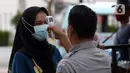 Pengunjung melakukan pengecekan suhu tubuh sebelum memasuki kawasan Kota Tua Jakarta, Kamis (29/10/2020). Libur panjang di masa pemberlakuan PSBB transisi Jakarta dimanfaatkan warga untuk mengunjungi lokasi-lokasi wiisata. (Liputan6.com/Helmi Fithriansyah)