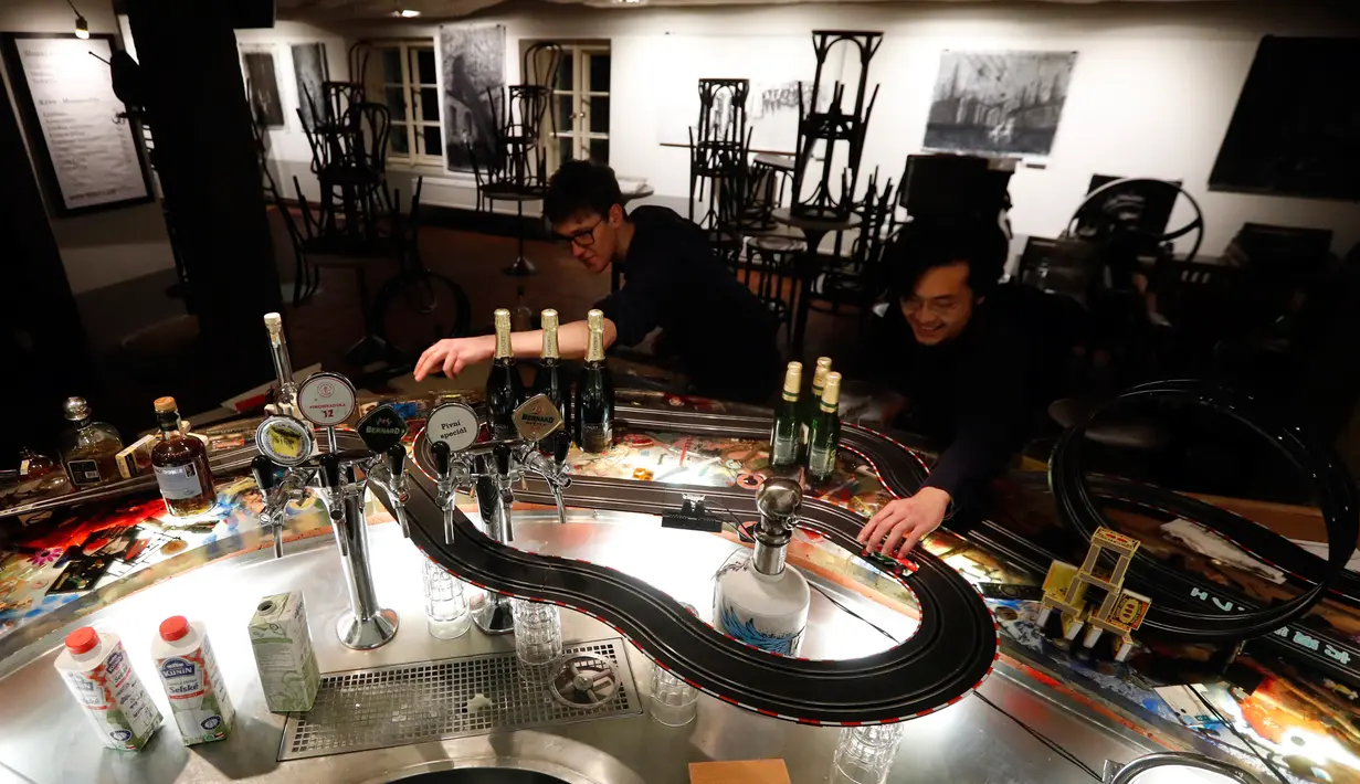 Pekerja menghabiskan waktu dengan bermain lintasan mobil balap mainan yang dipasang di sebuah bar di Praha, Republik Ceko, 15 Oktober 2020. Area bar menjadi lintasan mobil mainan yang bisa dimanfaatkan para karyawan untuk mengusir kebosanan saat menunggu pesanan. (AP Photo/Petr David Josek)