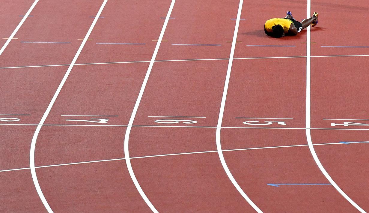 Pelari Jamaika, Usain Bolt terkapar di lintasan setelah terjatuh karena cedera di final 4x100 meter pada Kejuaraan Dunia Atletik di London, Sabtu (12/8). Bolt sempat tertatih-tatih sebelum akhirnya jatuh dan gagal melanjutkan lomba. (AP/Martin Meissner)