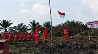 Personel Manggala Agni mengibarkan bendera dalam upacara kemerdekaan di lokasi kebakaran lahan. (Liputan6.com/M Syukur)