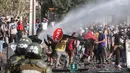 Demonstran saat bentrok dengan polisi di lingkungan miskin di Santiago, Chili, (18/5/2020). Pemerintah sebenarnya sudah mendistribusikan 2.000 paket bantuan kepada keluarga di area tersebut. Namun bantuan diberikan hanya kepada yang paling membutuhkan. (AP Photo/Esteban Felix)
