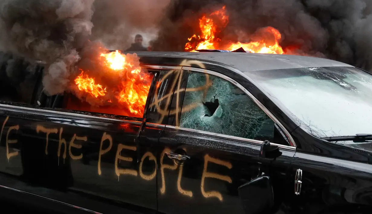 Sebuah mobil limusin dibakar oleh para pengunjuk rasa saat terpakir selama protes pelantikan Presiden Donald Trump di Washington, DC, AS, (20/1). selain membakar para pengunjuk rasa mencoret-coret mobil mewah tersebut. (AP Photo/John Minchillo)