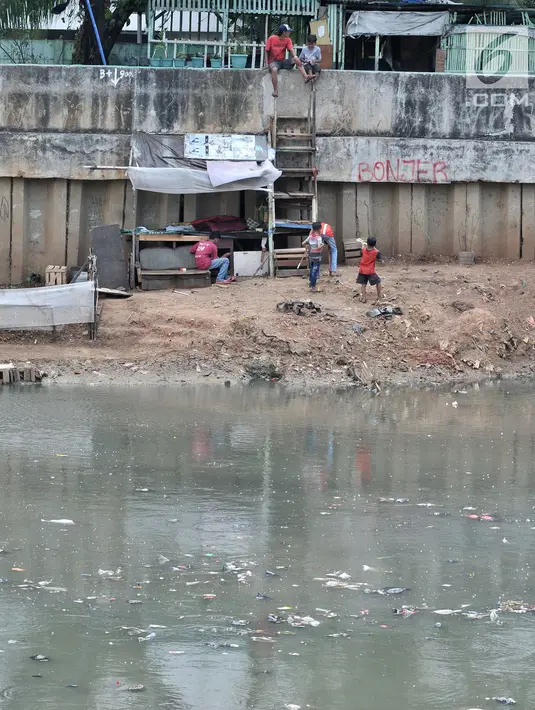 Anak-anak bermain di pinggir aliran Kanal Banjir Barat yang tengah dipenuhi sampah, Jakarta, Senin (22/10). Sampah yang memenuhi aliran kanal pencegah banjir tersebut didominasi plastik dan limbah rumah tangga. (Merdeka.com/Iqbal Nugroho)