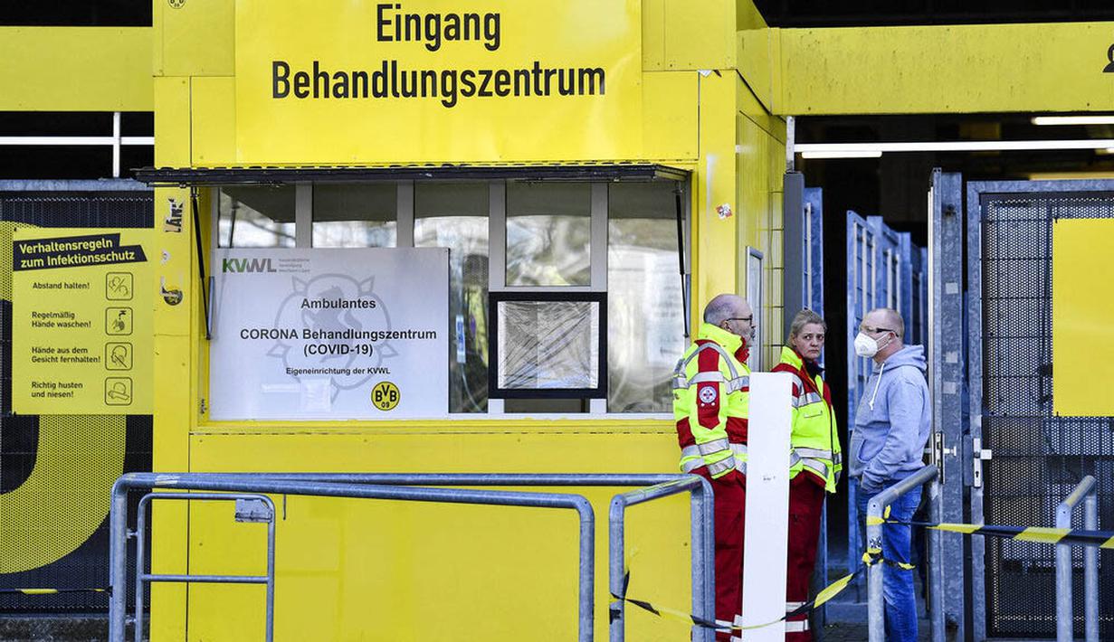 Petugas Kesehatan dengan menggunakan masker berjaga di depan Stadion Signal Iduna Park, Jerman, Sabtu (4/4/2020). Stadion Borussia Dortmund ini dialihfungsikan menjadi tempat pusat pengujian COVID-19. (AP/Martin Meissner)