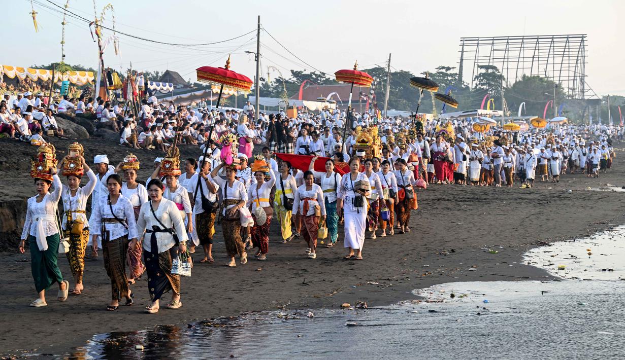 Melasti merupakan upacara adat yang bertujuan untuk menyucikan diri dan membersihkan alam dari energi negatif. Tampak dalam foto, umat Hindu saat mengikuti upacara doa Melasti di salah satu pantai di Denpasar, Bali, pada Senin 16 Maret 2026. (SONNY TUMBELAKA/AFP)