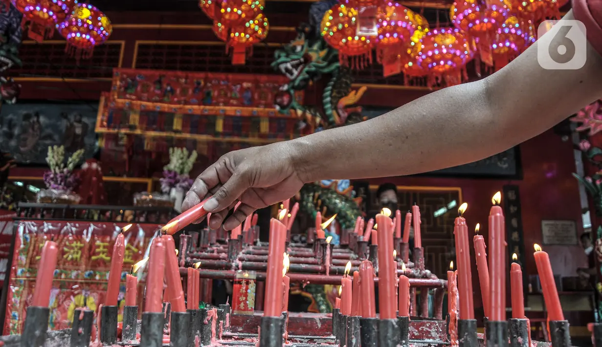 Warga keturunan Tionghoa menyalakan lilin saat sembahyang Tahun Baru Imlek 2573 Kongzili di Karet Semanggi, Jakarta, Selasa (1/2/2022). Pengurus Vihara Amurva Bhumi menerapkan protokol kesehatan dalam kegiatan sembahyang Imlek guna mencegah penularan Covid-19. (merdeka.com/Iqbal S Nugroho)