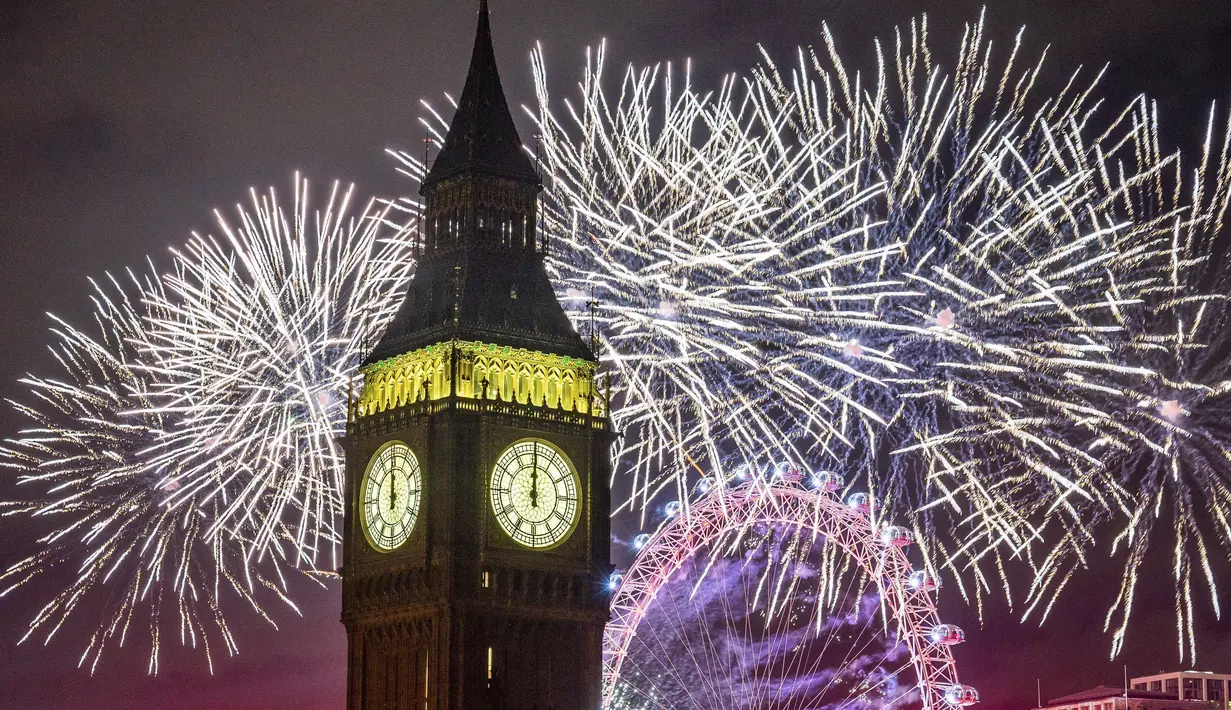 Kembang api menerangi langit di atas London Eye dan Elizabeth Tower, juga dikenal sebagai "Big Ben," di pusat kota London selama perayaan Tahun Baru pada Minggu (1/1/2022). Malam pergantian tahun identik dengan pesta kembang api. (Aaron Chown/PA via AP)