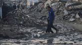 Warga Palestina berjalan di tengah bangunan yang hancur akibat serangan udara dan darat Israel di Kota Gaza, Selasa 6 Januari 2026. Komite Internasional Palang Merah (ICRC) terus berupaya menyalurkan bantuan ke Gaza. (AP Photo/Jehad Alshrafi)