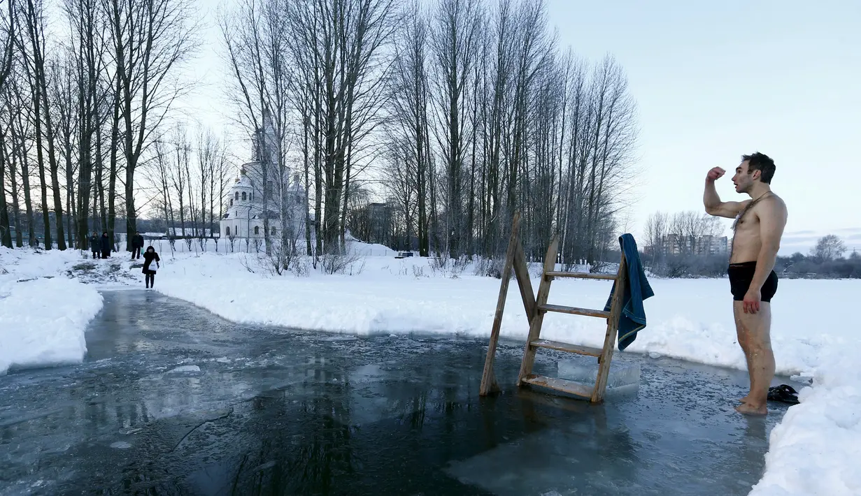 Seorang pria bersiap untuk mandi di dalam air es di danau dalam prosesi perayaan Epifani Ortodoks di Minsk, Belarusia (19/1/2016). Umat Kristen Ortodoks merayakan Epifani yang jatuh pada 19 Januari. (REUTERS/Vasily Fedosenko)