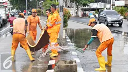 Semangat petugas membersihkan genangan air di Harmoni, Jakarta, Selasa (9/2). Buruknya sistem drainase membuat petugas terpaksa harus membersihkan genangan setiap kali hujan, meski dengan peralatan seadanya. (Liputan6.com/Immanuel Antonius)