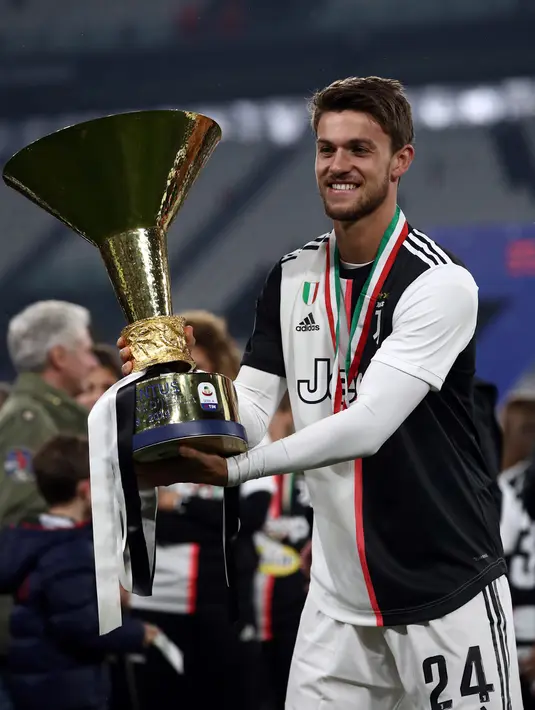 Bek  Juventus, Daniele Rugani berpose dengan trofi Juara Italia di akhir pertandingan Liga Serie A Italia setalah melwan Atalanta pada 19 Mei 2019 di Allianzstadium di Turin. Pemain 25 tahun ini dinyatakan positif terkena virus corona, yang diumumkan klub 11 Maret 2020. (AFP Photo/Isabella Bonotto)