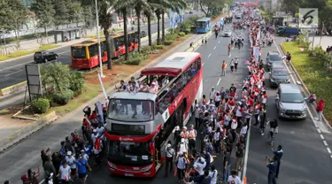 Bus tingkat dengan kap terbuka membawa pelari Torch Relay Asian Games 2018 di Jalan Jendral Sudirman, Jakarta, Sabtu (18/8). Hari terakhir kirab obor Asian Games ini api abadi dibawa dari Tugu Monas hingga Gelora Bung Karno. (Liputan6.com/ Fery Pradolo)