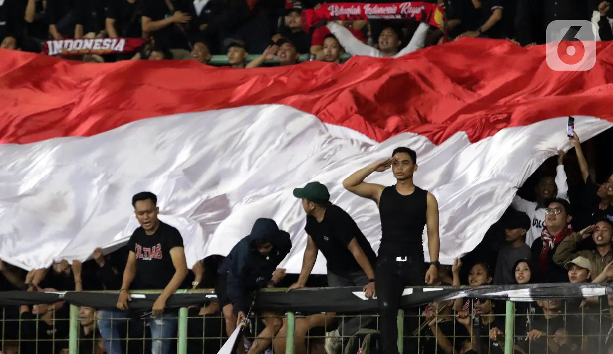 Suporter memberi hormat saat menyanyikan lagu kebangsaan Indonesia Raya jelang laga Timnas Indonesia U-19 melawan Vietnam U-19 pada kualifikasi grup A Piala AFF U-19 2022 di Stadion Patriot Candrabhaga, Bekasi, Jawa Barat, Sabtu (2/7/2022). Laga Timnas Indonesia U-19 melawan Vietnam U-19 berakhir imbang 0-0. (Liputan6.com/Helmi Fithriansyah)