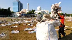 Pemulung memasukkan lembaran koran bekas usai pelaksanaan salat Idul Fitri 1436 H di Lapangan Masjid Agung Al Azhar, Jakarta, Jumat (17/7/2015). Sisa koran bekas menjadi rejeki tersendiri bagi para pemulung. (Liputan6.com/Yoppy Renato)