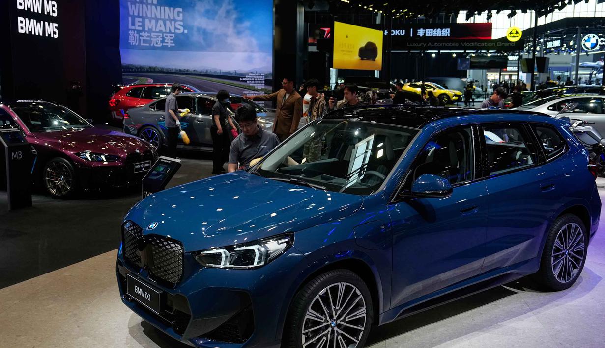 Beijing Auto Show atau Auto China 2026 berfokus pada kendaraan listrik (EV) canggih, mobil pintar, dan teknologi otonom dari berbagai pabrikan global dan lokal. Tampak dalam foto, petugas kebersihan mengelap model-model mobil BMW saat gelaran Beijing Auto Show 2026 atau Auto China 2026, Jumat 24 April 2026. (AP Photo/Andy Wong)