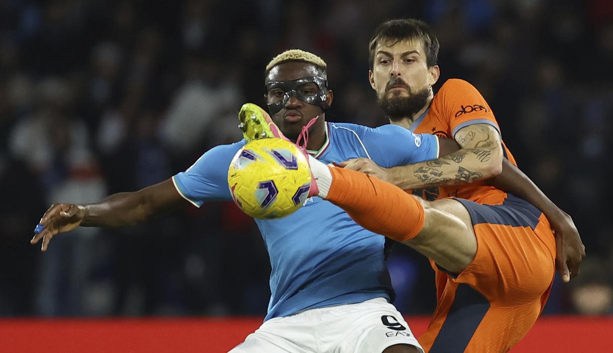 Penyerang Napoli, Victor Osimhen mencoba memblokir bek Inter Milan Francesco Acerbi menendang bola pada laga pekan ke-14 Serie A 2023/2024 di Stadio Diego Armando Maradona, Senin (04/12/2023) dini hari WIB. (Alessandro Garofalo/LaPresse via AP)