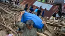 Penduduk desa mencari barang-barang dari rumah mereka sebelum mengungsi setelah banjir bandang di Kabupaten Luwu Utara, Sulawesi Selatan, Rabu (15/7/2020).  Akibat banjir bandang tersebut mengakibatkan 16 orang meninggal dunia dan ratusan rumah tertimbun lumpur. (Hariandi HAFID / AFP)