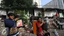 Warga membawa barang berharga saat alat berat merobohkan bangunan di kawasam Rawajati, Jakarta, Kamis (1/9). Penertiban tersebut menyebabkan warga terpaksa menyelamatkan barang berharga mereka ke tepi rel kereta api. (Liputan6.com/Immanuel Antonius)
