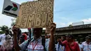 Seorang peserta aksi menunjukkan sebuah poster saat melakukan mogok kerja dan unjuk rasa di Depot Pertamina Plumpang, Jakarta, Selasa (1/11). Para Awak Mobil Tangki Pertamina menuntut perusahaan menghapus sistem outsourcing. (Liputan6.com/Faizal Fanani)