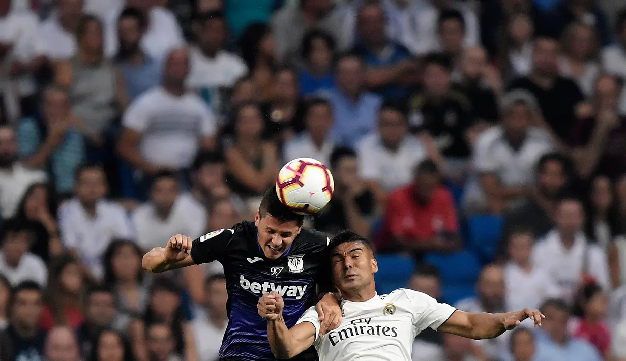 Gelandang Real Madrid, Casemiro berebut bola dengan pemain Leganes, Guido Carrillo pada laga leg pertama babak 16 besar Copa del Rey di Santiago Bernabeu, Rabu (9/1). Real Madrid sukses mengandaskan Leganes dengan skor 3-0. (GABRIEL BOUYS / AFP)