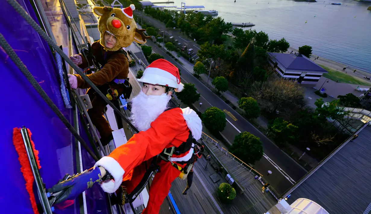 Dua petugas pembersih kaca jendela berkostum Santa Claus dan rusa membersihkan kaca-kaca gedung bertingkat di pusat perbelanjaan di Tokyo, Kamis (21/12). Para pekerja ini melakukannya untuk merayakan Natal 25 Desember. (AP/Shizuo Kambayashi)