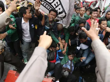Sejumlah mahasiswa dari BEM Se-Jabodetabek terjatuh saat menggelar aksi unjuk rasa di depan Istana Negara, Kamis (12/1). Dalam aksinya mereka menuntut Presiden Jokowi-JK untuk membuat kebijakan yang pro terhadap rakyat. (Liputan6.com/Faizal Fanani)