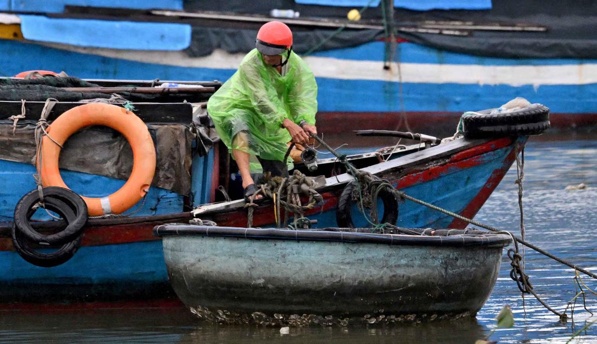 Badan Meteorologi Nasional Vietnam memperkirakan, Topan Kalmaegi akan disertai gelombang setinggi delapan meter atau 26 kaki dan badai yang kuat. Tampak dalam foto, seorang pria mengikat perahu untuk melindunginya dari dampak Topan Kalmaegi di Pelabuhan Perikanan Quy Nhon, Provinsi Gia Lai, Vietnam Tengah, pada 6 November 2025. (Nhac NGUYEN/AFP)