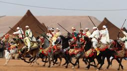 Aksi penunggang kuda saat upacara pembukaan Festival Tan-Tan Moussem Berber ke-14 di Kota Tan-Tan, Maroko, Jumat (6/7). Festival ini merupakan pertemuan terbesar suku nomaden di Afrika Utara. (KARIM SAHIB/AFP)