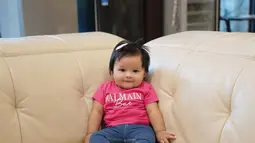 Mengenakan kaos merah muda, Baby Ameena bersandar di sofa. (Foto: Instagram/ ameenaatta)