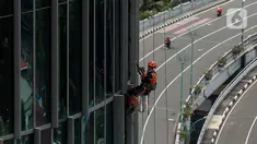 Pekerja bergelantungan membersihkan bagian luar gedung di kawasan Kuningan, Jakarta, Minggu (19/12/2021). Pekerja ini harus bergelantungan dengan seutas tali untuk membersihkan dinding-dinding gedung bertingkat yang tingginya kurang lebih mencapai 150 meter. (Liputan6.com/Johan Tallo)