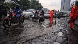 Petugas dari Dinas Kebersihan membuang genangan air kedalam selokan usai hujan deras dikawasan Tugu Tani, Jakarta, Kamis (12/10). Tingginya curah hujan membuat genangan disisi jalan. (Liputan6.com/Faizal Fanani)