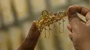 <p>Seorang pelanggan memegang perhiasan emas selama festival Hindu 'Akshaya Tritiya', hari keberuntungan dalam kalender Hindu untuk membeli barang-barang berharga, di ruang pamer perhiasan di Chennai, India, Selasa (3/5/2022). Membeli emas adalah kegiatan yang populer di Akshaya Tritiya, karena ini adalah simbol utama kekayaan dan kemakmuran. (Arun SANKAR / AFP)</p>