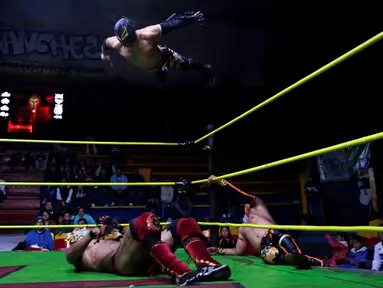 Seorang penggulat yang dikenal Aero Boy melompat menyerang lawannya, Dragon Rojo Jr yang terbaring di atas ring saat pertandingan gulat di Arena Neza di pinggiran Mexico City, Meksiko (28/10). (Reuters/ Carlos Jasso)