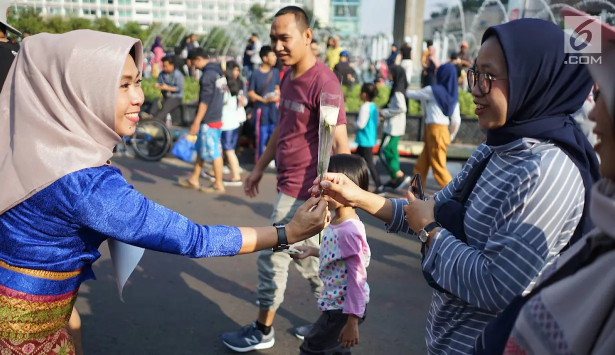 Sejumlah relawan membagikan bunga mawar ke warga saat berlangsungnya kegiatan car free day di kawasan Bundaran HI, Jakarta, Minggu (30/6/2019).  Aksi 1000 bunga mawar itu sebagai bentuk rasa syukur atas kemenangan pasangan Jokowi-Ma'ruf Amin di Pilpres 2019. (Liputan6.com/Immanuel Antonius)