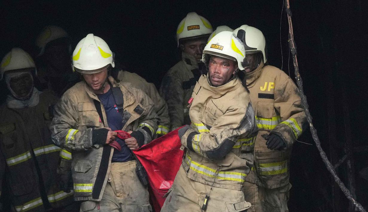 Kesemua korban dibawa ke Instalasi Forensik RS Polri untuk proses identifikasi. Tampak dalam foto, tim personel dari Dinas Penanggulangan Kebakaran dan Penyelamatan mengevakuasi jenazah korban kebakaran di Jakarta, Selasa 9 Desember 2025. (AP Photo/Dita Alangkara)