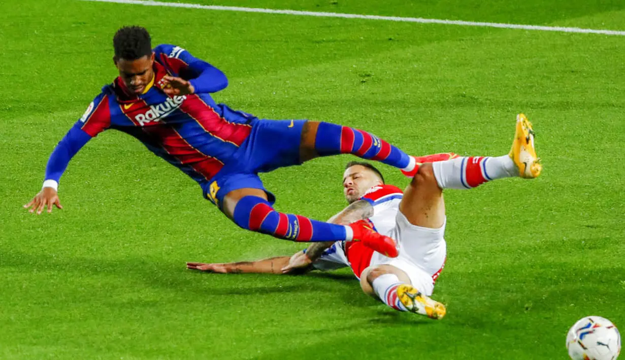 Pemain Barcelona, Junior Firpo, terjatuh saat berebut bola dengan pemain Alaves, Edgar Mendez, pada laga Liga Spanyol di Stadion Camp Nou, Sabtu (14/2/2021). Barcelona menang dengan skor 5-1. (AP Photo/Joan Monfort)