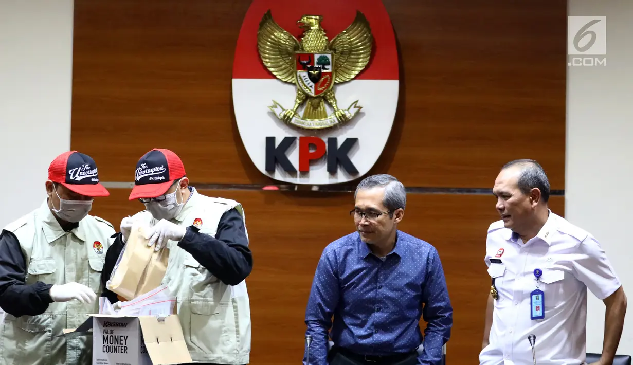 Petugas menunjukkan barang bukti Rp1,2 miliar disaksikan Wakil Ketua KPK Alexander Marwata dan Irjen Kemenkum HAM Jhoni Ginting saat keterangan pers OTT penanganan perkara penyalahgunaan izin tinggal Kantor Imigrasi Kelas I Mataram, NTB di Gedung KPK, Jakarta (28/5/2019). (Liputan6.com/Johan Tallo)